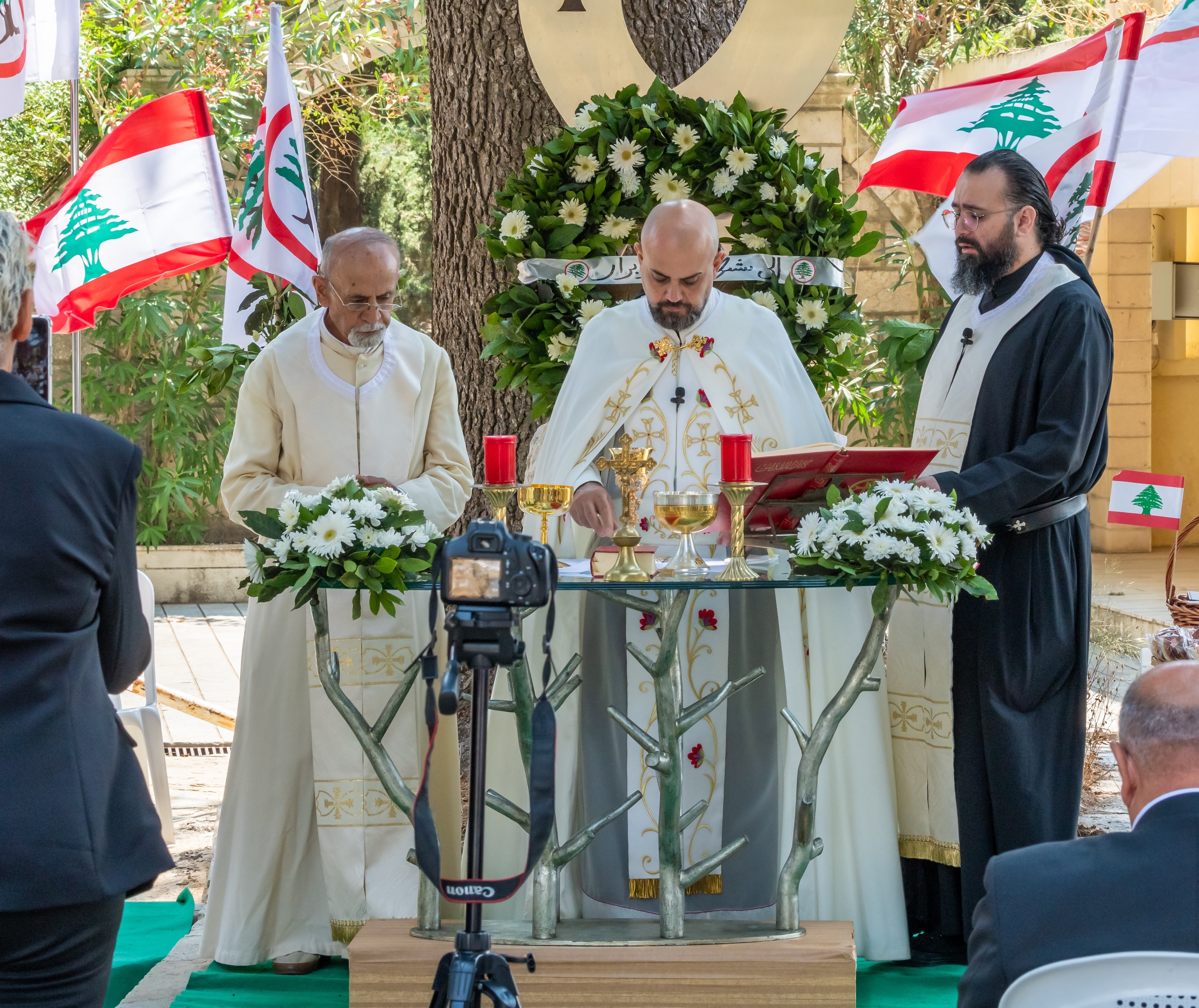 Lebanese Christian clergy celebrate Mass in Qartaba surrounded by Lebanese flags and Lebanese Forces symbols.