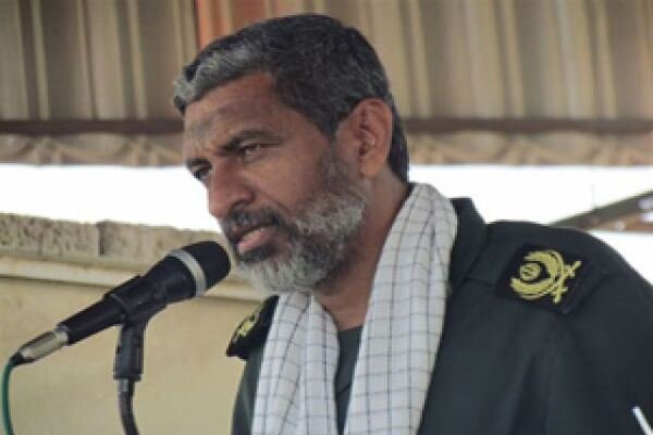 IRGC Navy commander Ali Azmaei speaks at a microphone in military uniform.