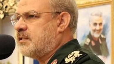 IRGC spokesman Hossein Mohebi speaks at a microphone in military uniform.