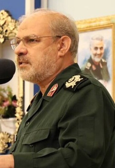 IRGC spokesman Hossein Mohebi speaks at a microphone in military uniform.