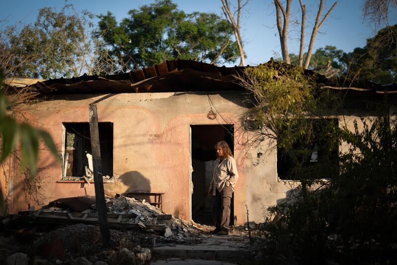 An Israeli woman stands outside a burned and damaged home in Kibbutz Nir Oz.