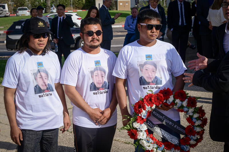 Mourners hold a wreath during a farewell ceremony for Thai national Sonthaya Oakkharasr at Ben Gurion Airport.