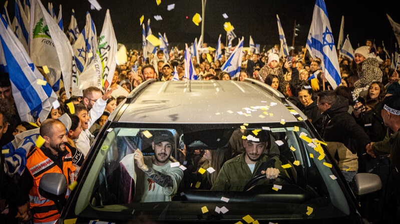 Former hostage Eliya Cohen returns home in Tzur Hadassah as supporters surround his vehicle with Israeli flags.