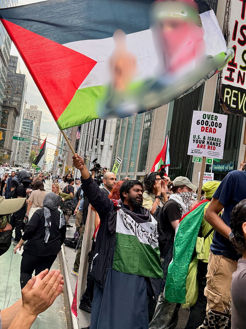 A protester in New York waves a Palestinian flag displaying an image associated with Hamas spokesperson Abu Obeida.