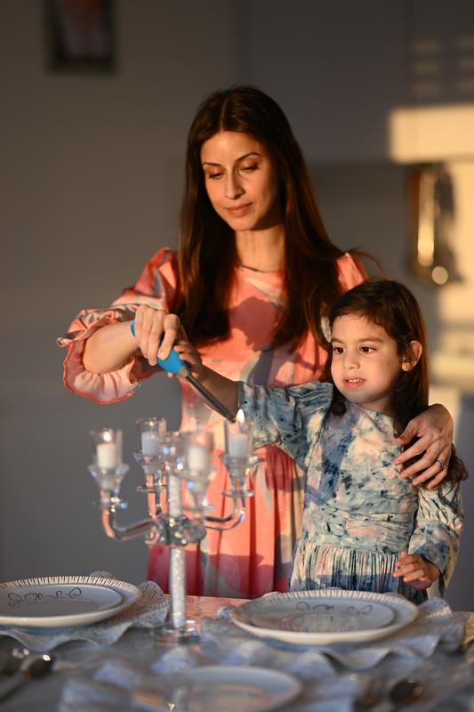 Mother and daughter lighting Shabbat candles Friday night.