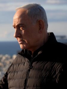 Prime Minister Benjamin Netanyahu looks ahead in an outdoor setting.