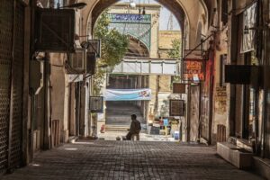 Traditional covered market street in Iran with shops, Persian signage and a pedestrian.