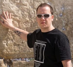 Swedish Christian influencer Andreas Fagerbakke standing with his hand on the Western Wall in Jerusalem.