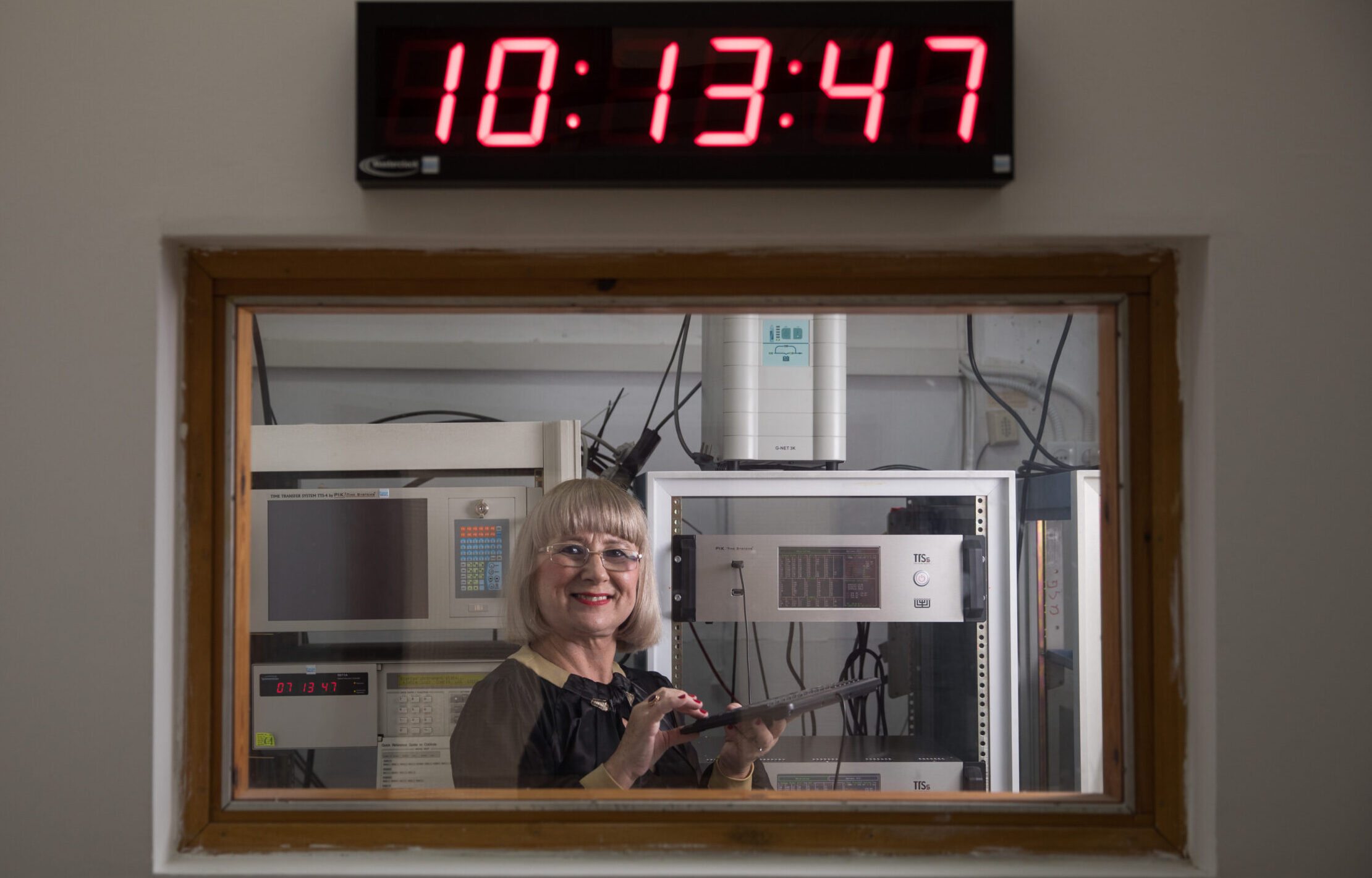 Dr. Nadya Goldovsky standing inside the National Physics Laboratories in Jerusalem beneath a digital clock.