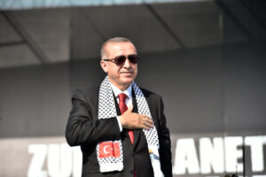 Turkish President Recep Tayyip Erdoğan wearing sunglasses and a Turkish-Palestinian scarf at a public event.