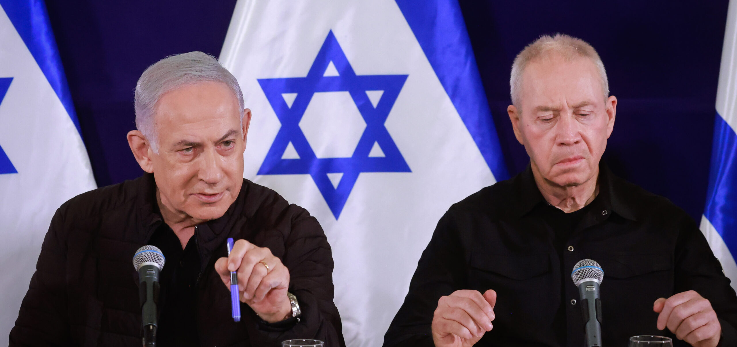 Benjamin Netanyahu, Yoav Gallant and Benny Gantz at a joint press conference with Israeli flags behind them.
