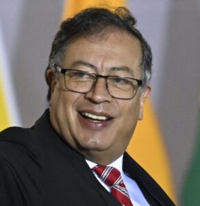 Colombian President Gustavo Petro smiling in a suit and red tie