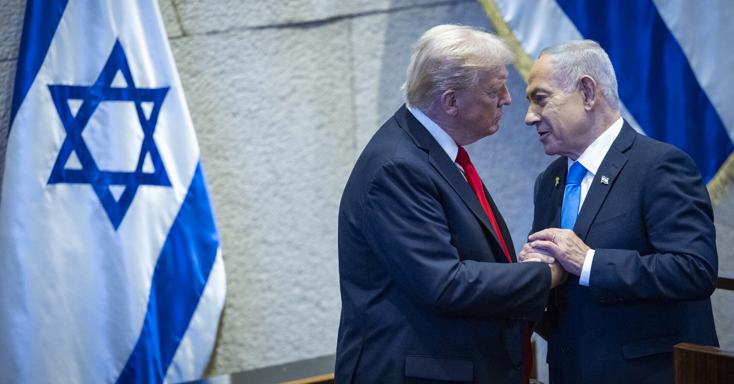 Donald Trump and Benjamin Netanyahu speak together at the Knesset in Jerusalem with Israeli flags behind them.