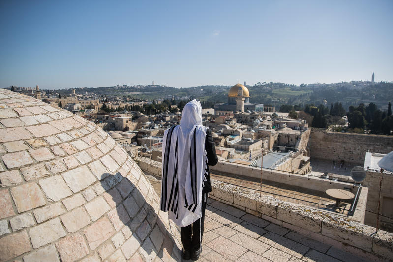 A Jewish man covers himself with a tallit (large prayer shawl) while praying near the Western Wall, Jerusalem.