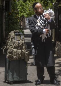 Haredi IDF soldier holding a Torah wrapped in a tallit in Jerusalem.