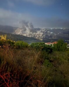 A large smoke cloud rises over a valley in southern Lebanon at night.