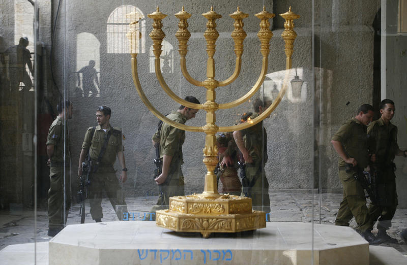 IDF soldiers pass a Menorah in the Jewish Quarter of the Old City of Jerusalem. A menorah, is a seven branched candelabrum lit by olive oil in the Tabernacle and the Temple in Jerusalem. 
