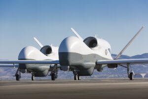 Two MQ-4C Triton unmanned aerial vehicles on a tarmac in Palmdale, California.