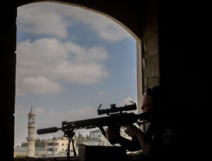 Silhouetted sniper holding a rifle inside a structure