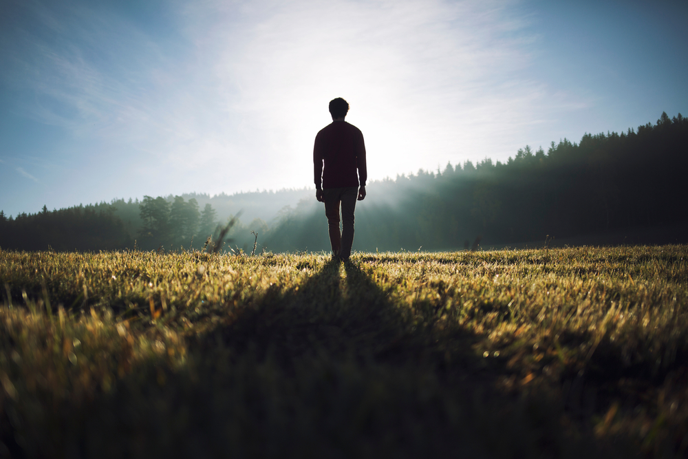 man walking in field, silhouette