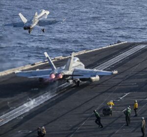 U.S. Navy fighter jets launching from the deck of the USS Abraham Lincoln aircraft carrier at sea.