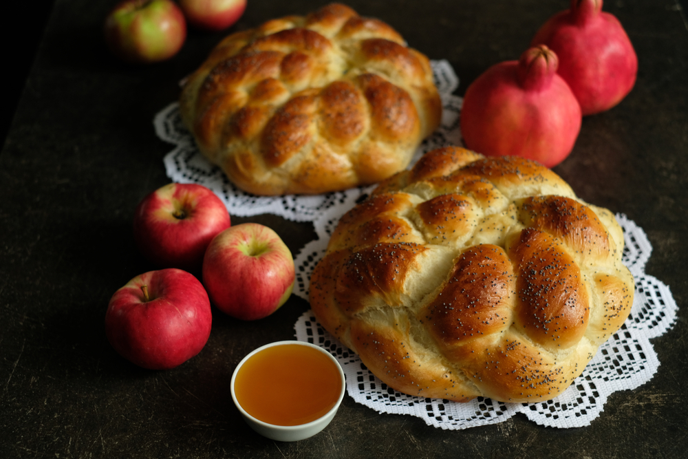 two homemade round challahs with honey, apples and pomegranates