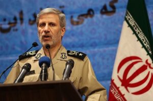 Iranian Army Commander Major General Amir Hatami speaks at a podium beside the Iranian flag.