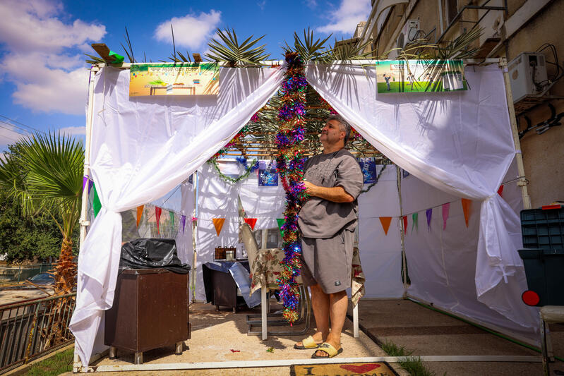 man decorating sukkah in israel