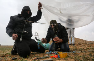 Young Palestinian men preparing a flammable object near the Israel-Gaza border east of Rafah.