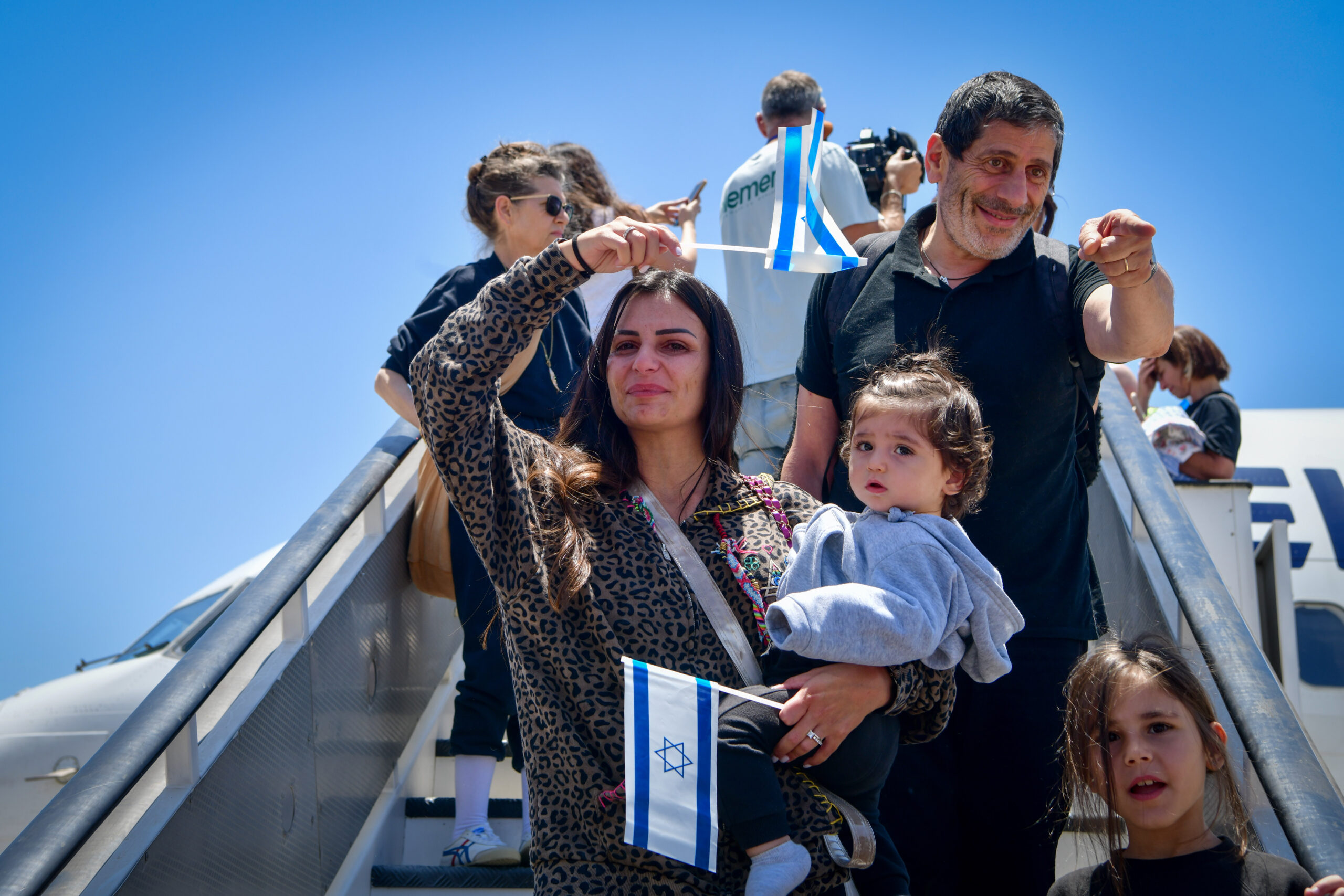 New immigrants arrive in Israel carrying Israeli flags.