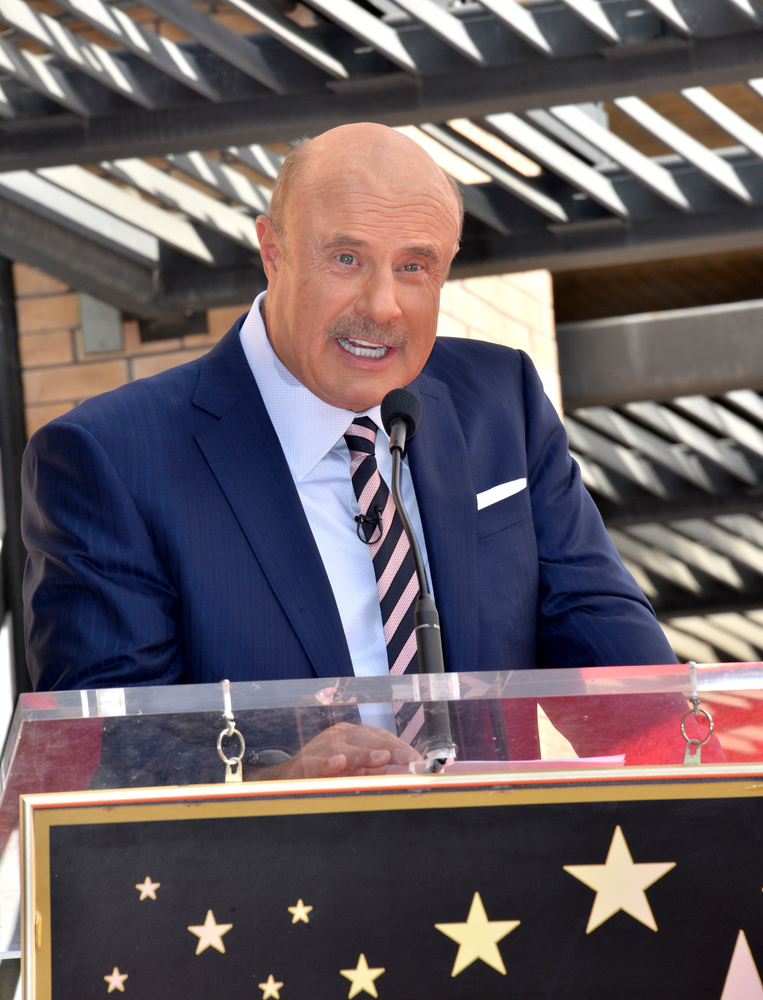 Dr phil in a suit at a podium speaking in LA
