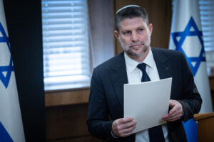 Israeli Finance Minister Bezalel Smotrich holding papers at a press conference in Jerusalem.