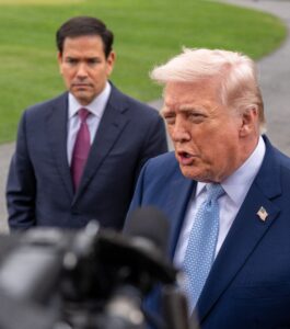 President Donald Trump speaks to reporters with Marco Rubio standing behind him.