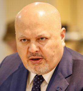 Karim Khan speaking while wearing a suit and tie.