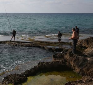 People fishing along the rocky shore at Achziv Beach in northern Israel