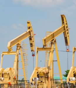 Oil pumpjacks operating under a blue sky.