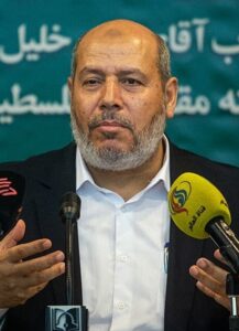 Khalil al-Hayya speaks at a press conference in front of microphones.
