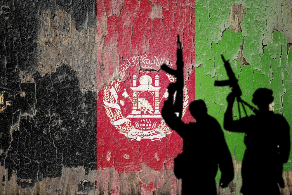 Flag of Afghanistan painted on the cracked wall with terrorist shadow.