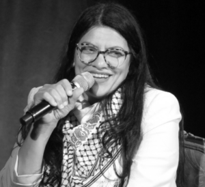 Congresswoman Rashida Tlaib speaks into a handheld microphone at an event.