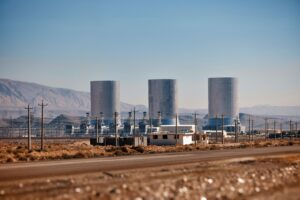 Power plant with large cooling towers in a desert landscape.