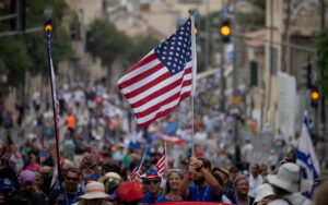Christian Evangelists and Israelis marching in Jerusalem with American and Israeli flags.