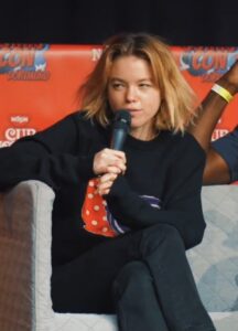 Milly Alcock speaking into a microphone at German Comic Con Dortmund.