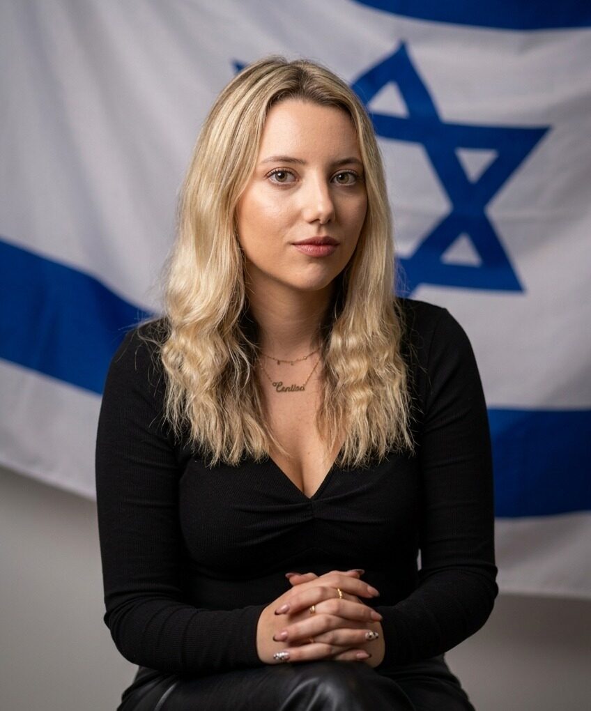 Turku Avci seated in front of an Israeli flag.