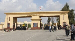 The Rafah crossing area at the Egypt-Gaza border with people standing near the gate.