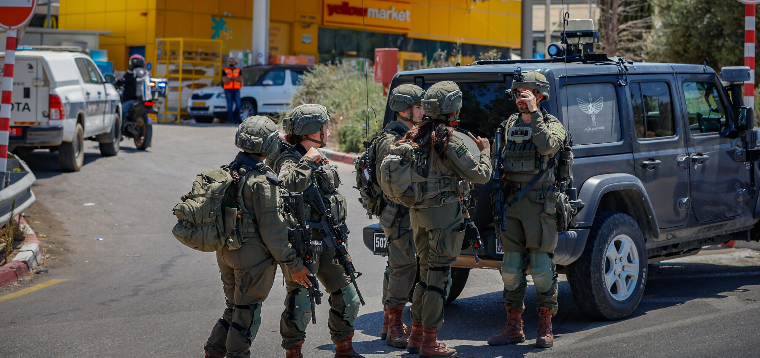 Israeli security forces stand near a gas station after a terror attack near Kochav Yair.
