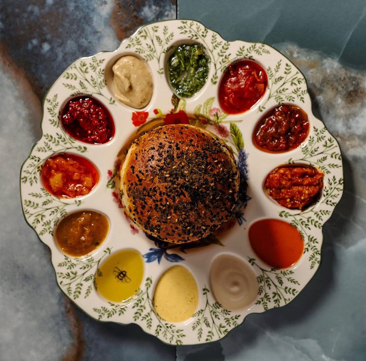 A plated restaurant dish with bread surrounded by colorful sauces and spreads.