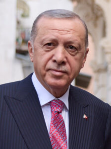 Turkish President Recep Tayyip Erdoğan wearing a dark suit and red tie.