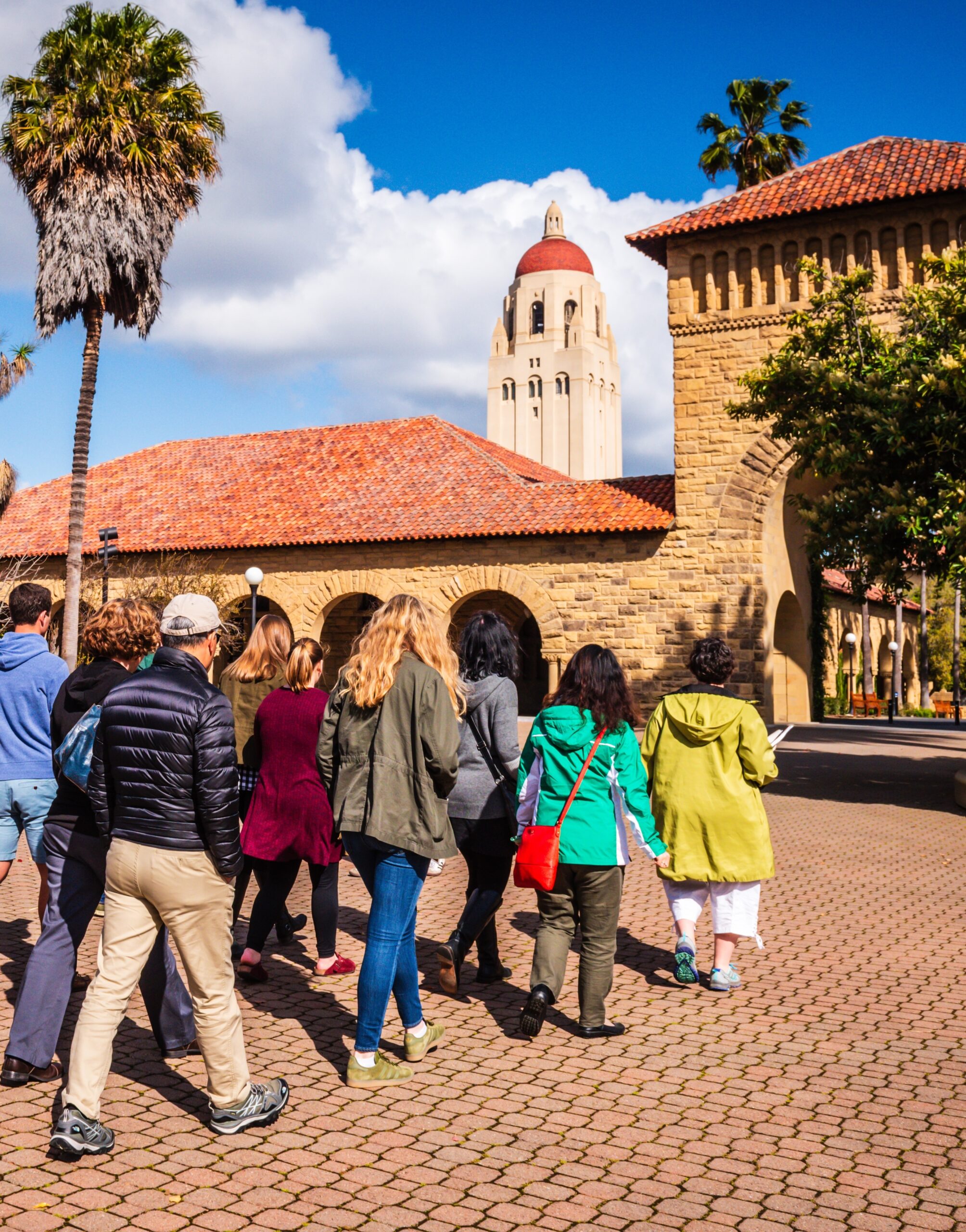 A group of people walks through the Stanford University campus.