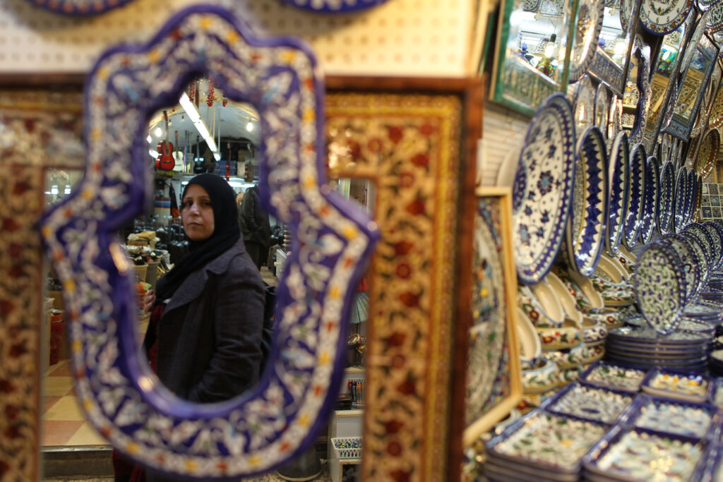 An Arab woman in a hijab is reflected in a mirror for sale in the Old City of Jerusalem.