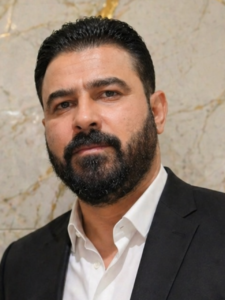 Ali Al-Zaidi wearing a dark suit and white shirt.